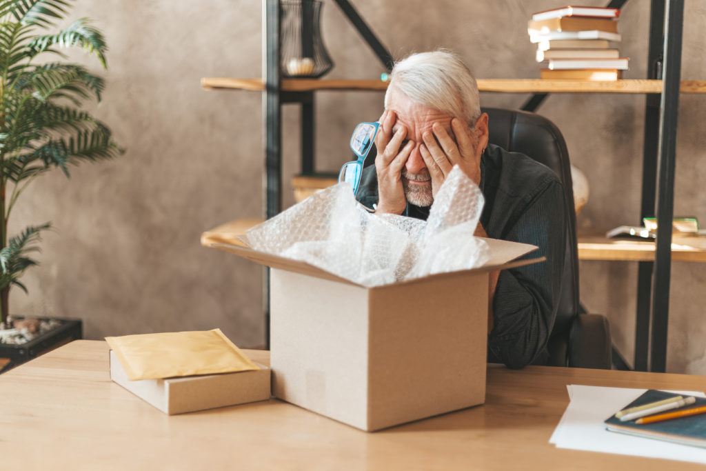 Damaged package. The elderly man at the table at home closed his eyes, broken goods. Postal delivery insurance