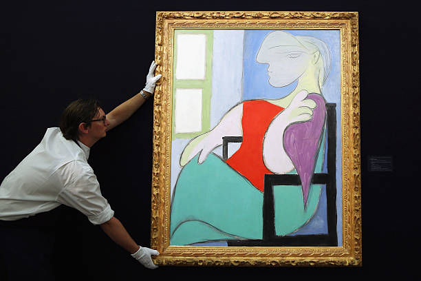 LONDON, ENGLAND - JANUARY 31:  A Sotheby's employee poses with a painting by Pablo Picasso entitled 'Femme assise pres d' une fenetre,' 1932, on January 31, 2013 in London, England. The piece makes up a selection of works by artists including Monet, Miro, Picasso and Richter and is estimated to sell for between 25-35 Million GBP at auction in the 'Impressionist and Modern Art' evening sale at Sotheby's auction house on February 5, 2013.  (Photo by Dan Kitwood/Getty Images)